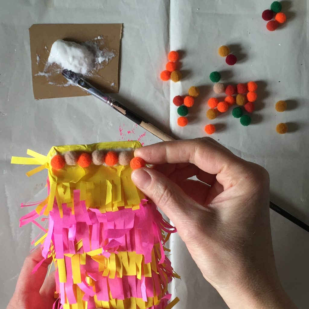 sustainable party crafts pinata being decorated with pompoms