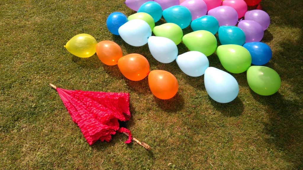strands of balloons and an umbrella ready to build a garden party balloon den