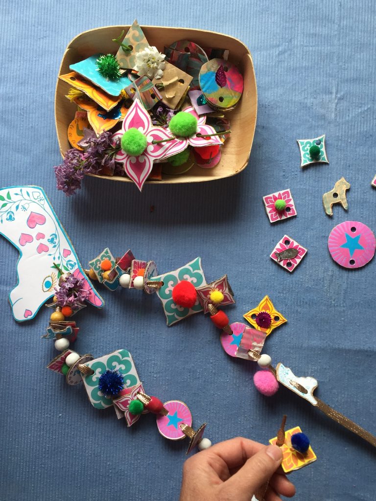 kids thread cardboard shapes onto ribbon to create colourful and sustainable junk necklaces