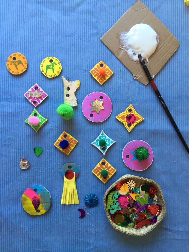 kids decorate recycled cardboard shapes with pompoms and sequins to make sustainable junk unicorn necklaces free printable